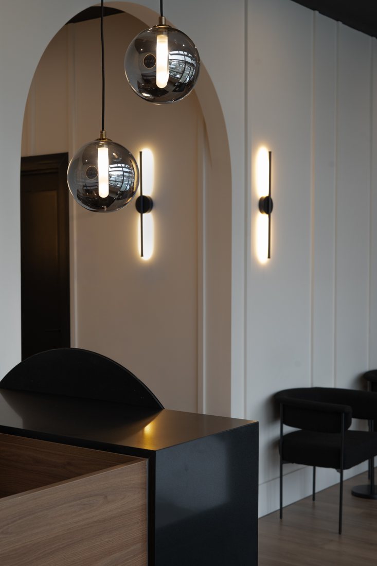 Clinic reception with arched wall and glass pendant lights